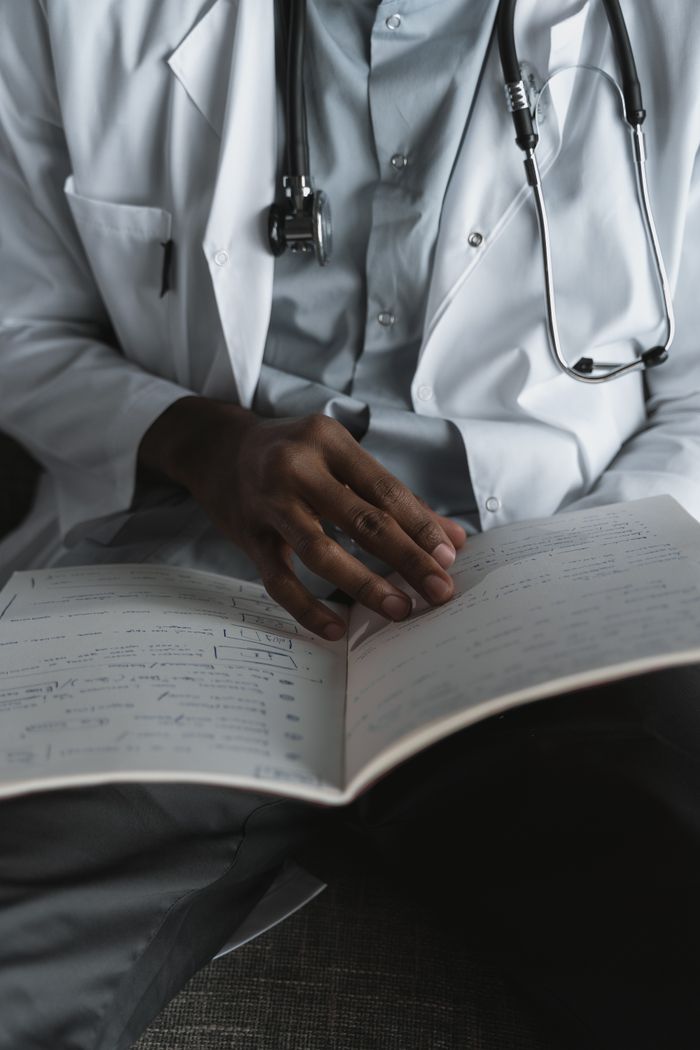 services-02 Close-up of a doctor reading medical notes, wearing a stethoscope, symbolizing diligent medical research and study.